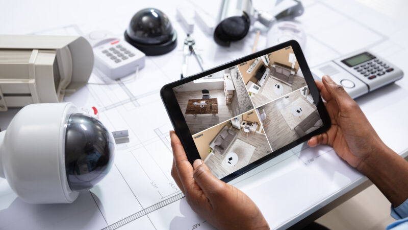 Person Watching Footage On Tablet With Security Equipment